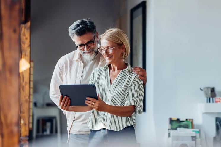 A man and woman looking at a tablet, smiling