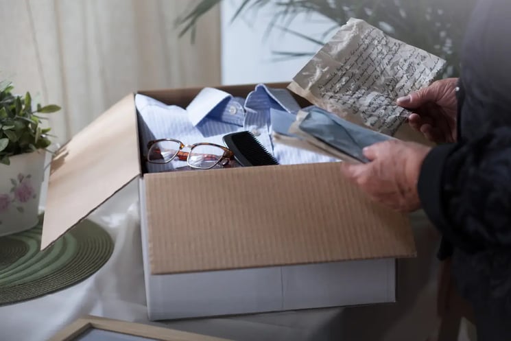 A box of belongings and hands holding a letter