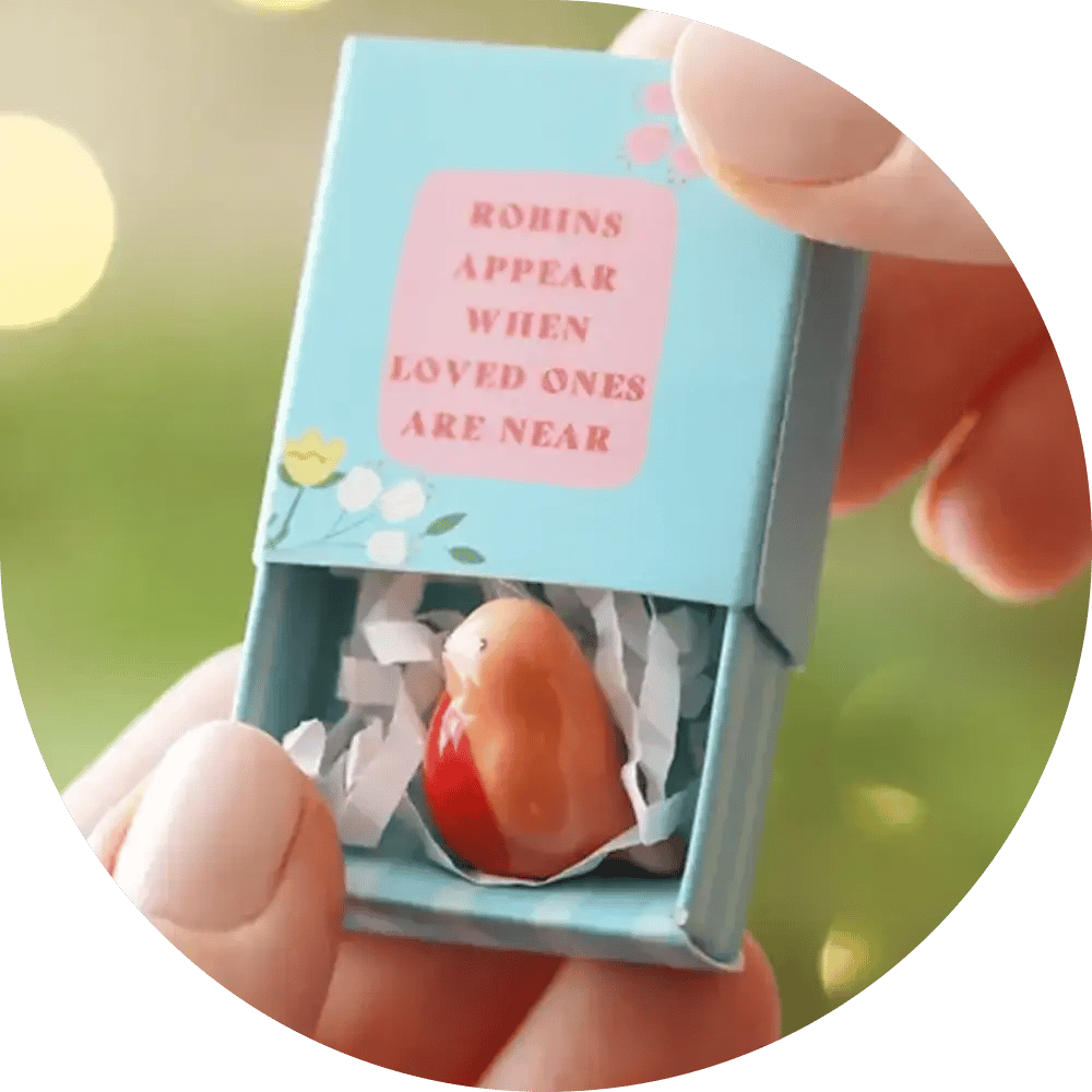 A small matchbox with a tiny ceramic robin inside