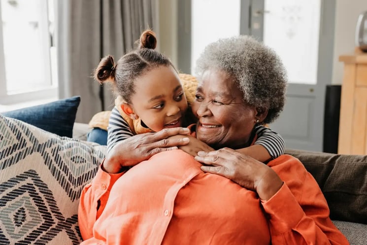 A woman and young girl embracing each other, smiling 