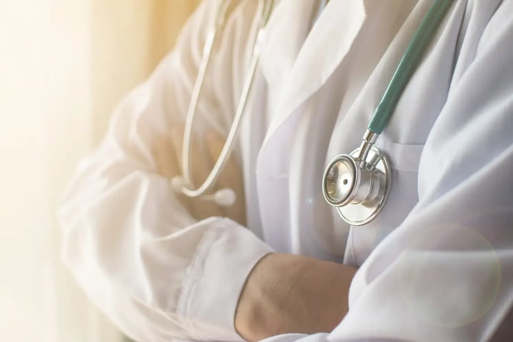 A doctor with arms crossed and stethoscope around their neck 