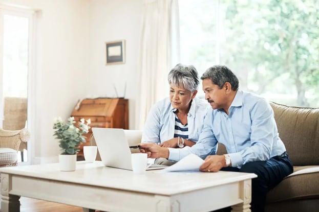 A couple sat on a sofa looking at a laptop