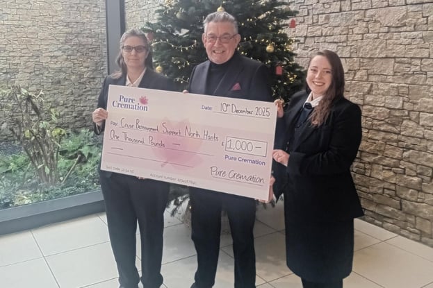 Two women and one man smiling at the camera, holding a big cheque