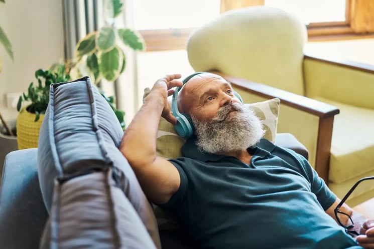 A man wearing headphones, lying on a sofa