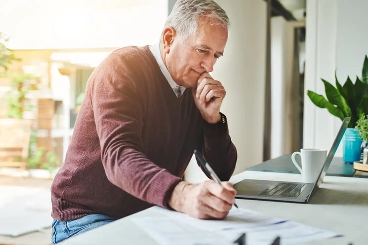 A man doing paperwork by his laptop