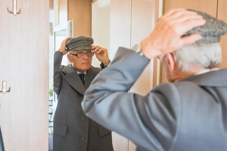A man getting dressed, looking in the mirror