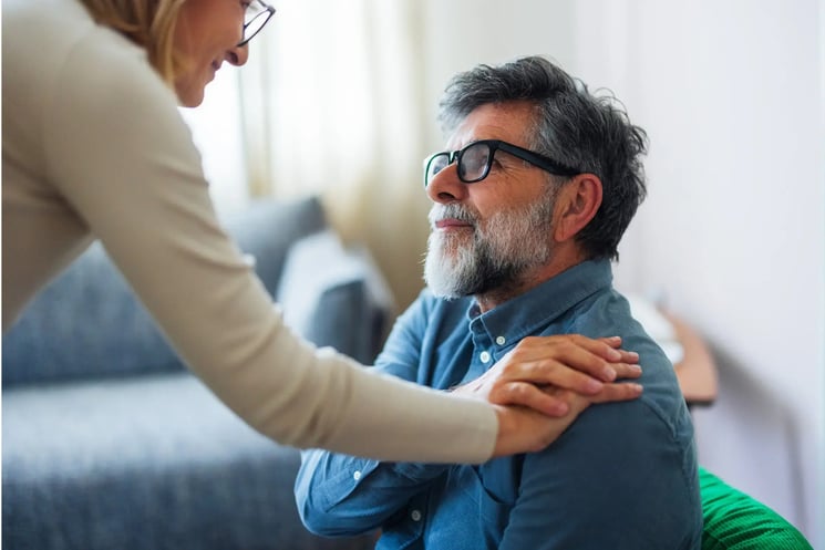 A woman puts her hand on a man's shoulder.