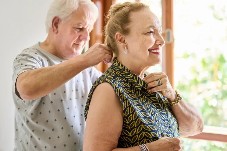 A man helping a woman put on a necklace