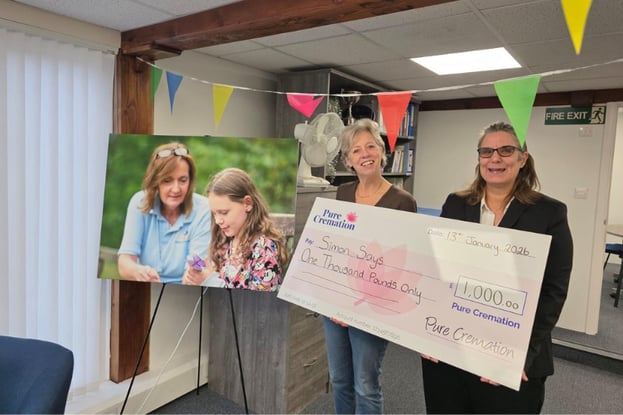 Two women smiling at the camera, holding a big cheque